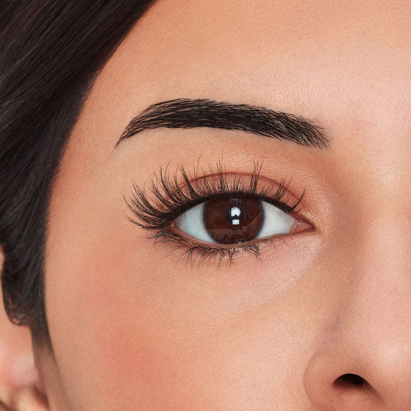 Close-up of a person's eye with long, dark eyelashes and well-groomed eyebrows.